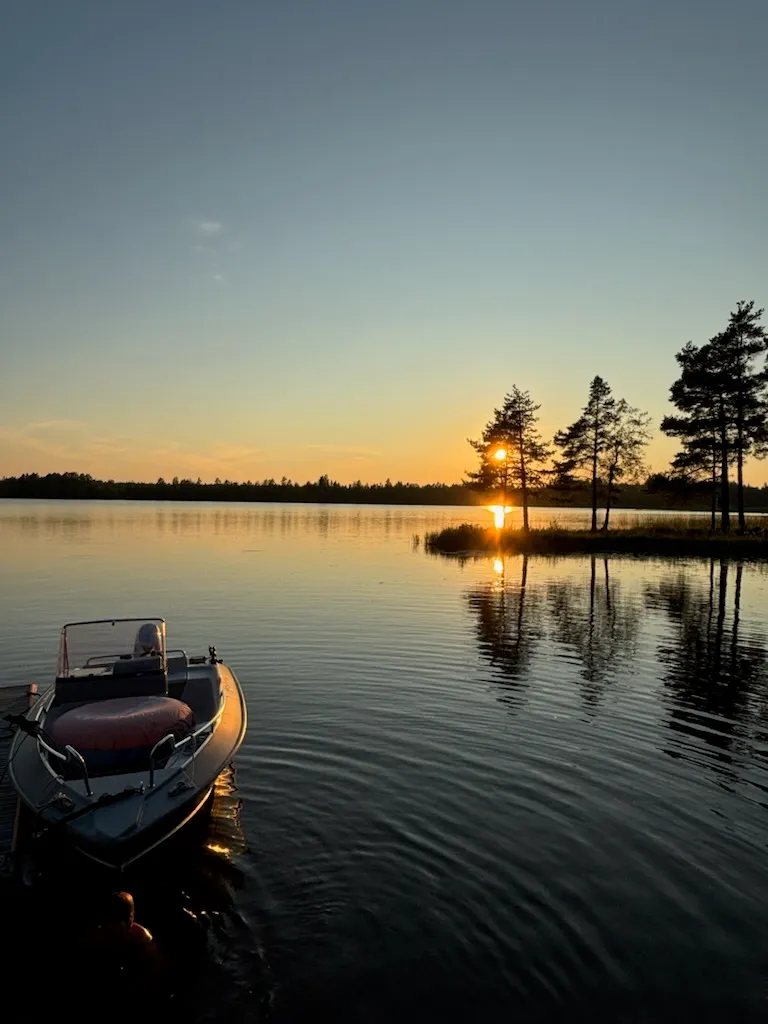 Båt vid strandkanten i solnedgång över Dalälven.