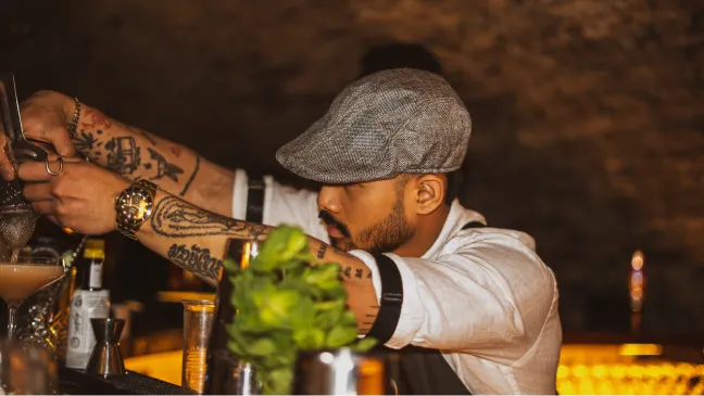 Bartender som gör i ordning en drink med mynta vid baren.