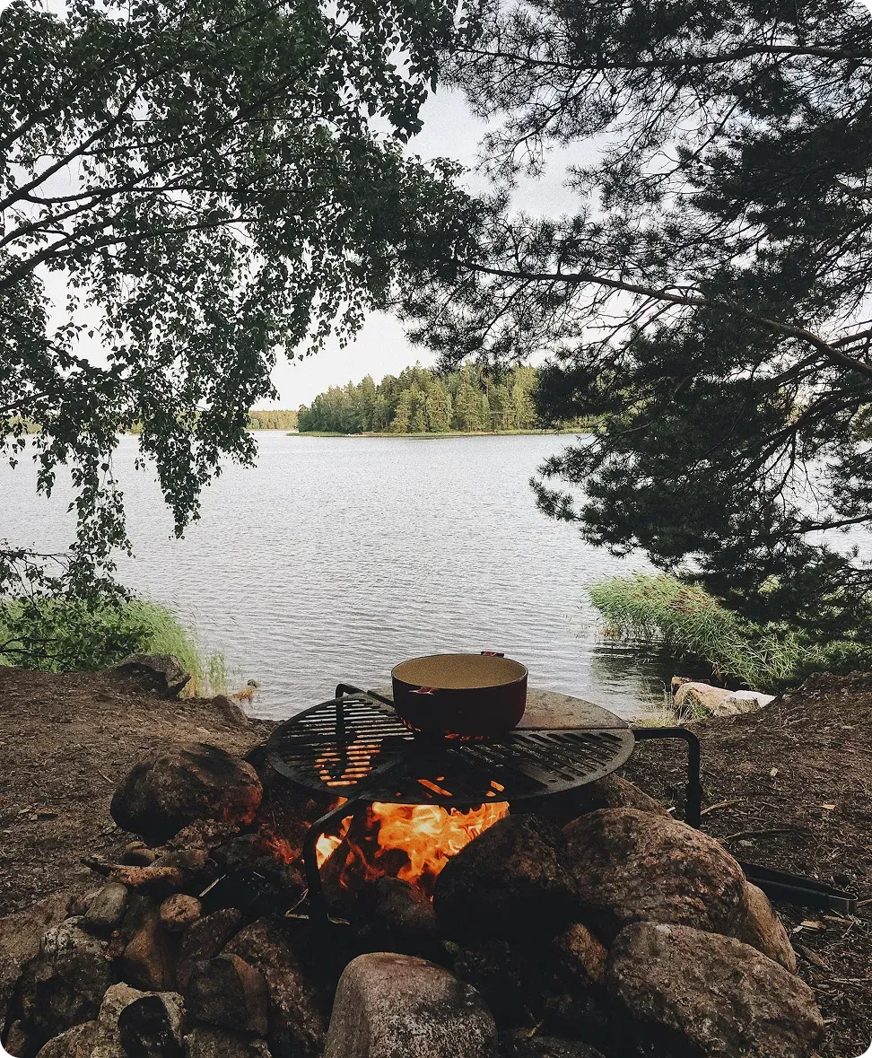 Eldstad vid sjön omgiven av skog.