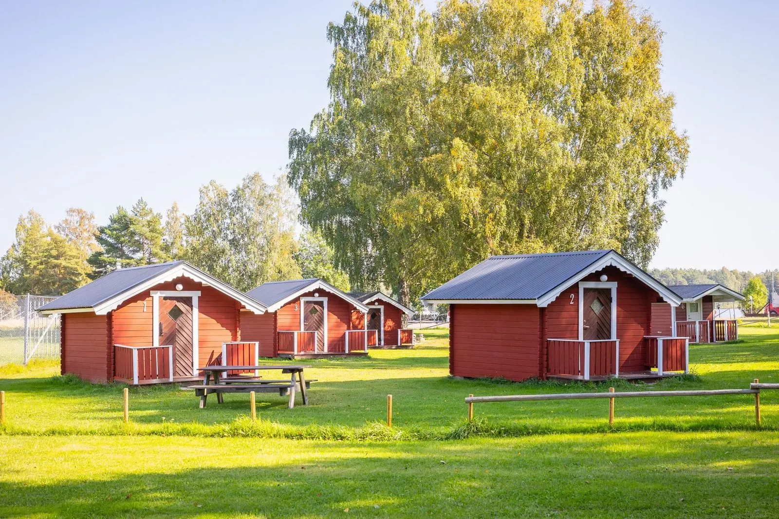 Små röda stugor vid vattnet omgivna av skog och Söderfors natur.