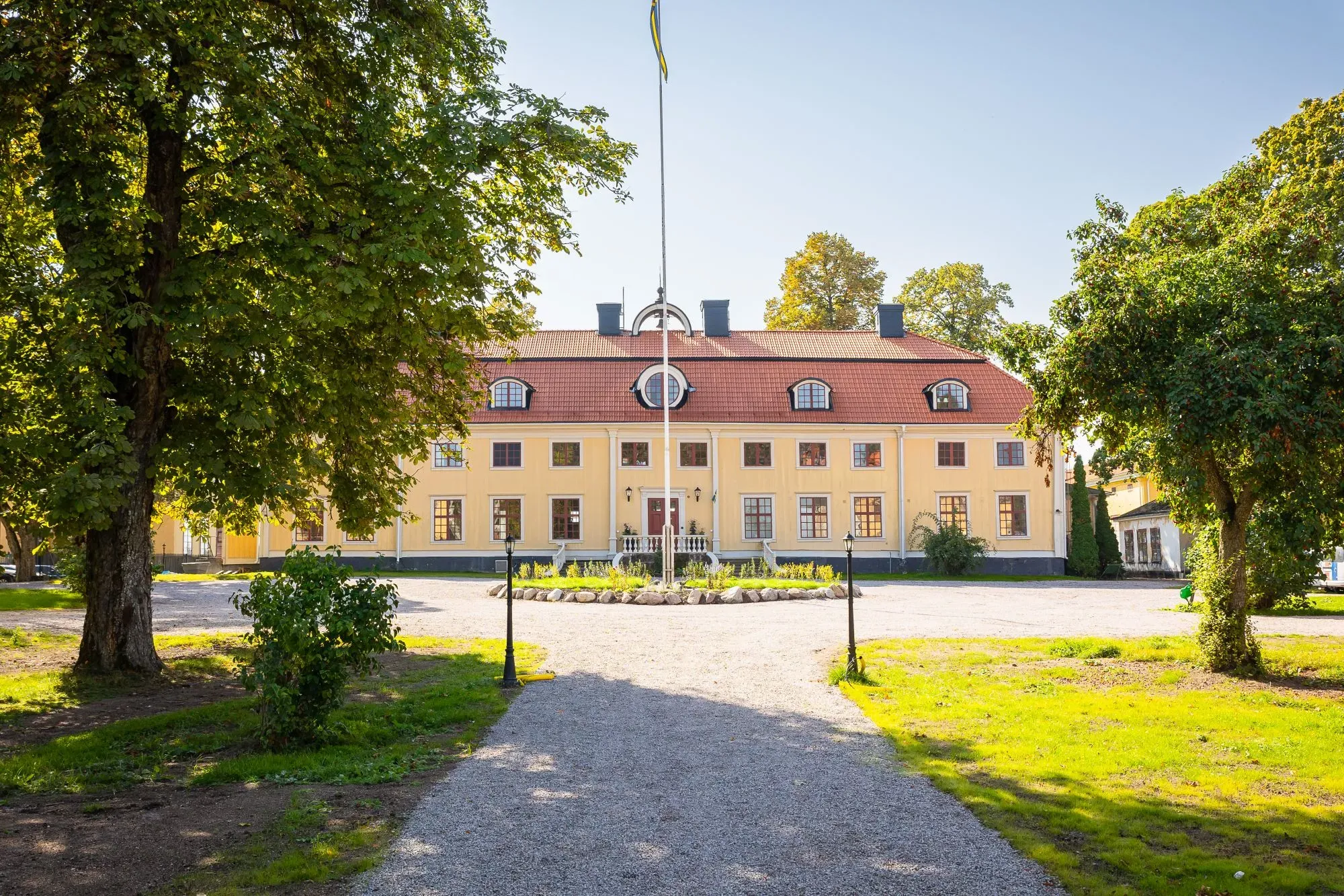 Söderfors Herrgårds historiska huvudbyggnad och flyglar sedda från trädgården.