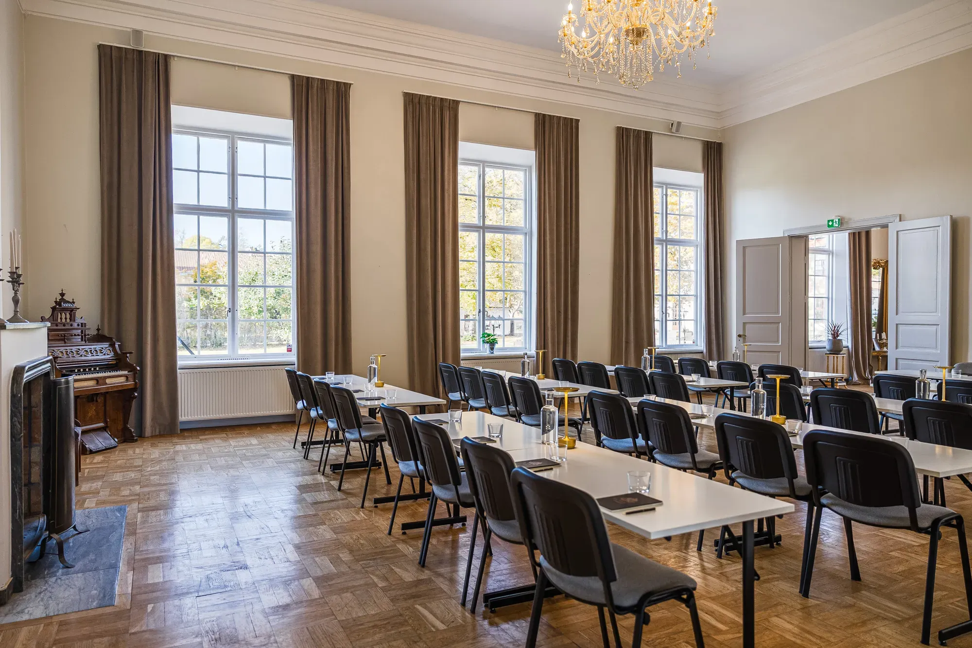Ankarström möblerad i klassrumssittning under kristallkronor.