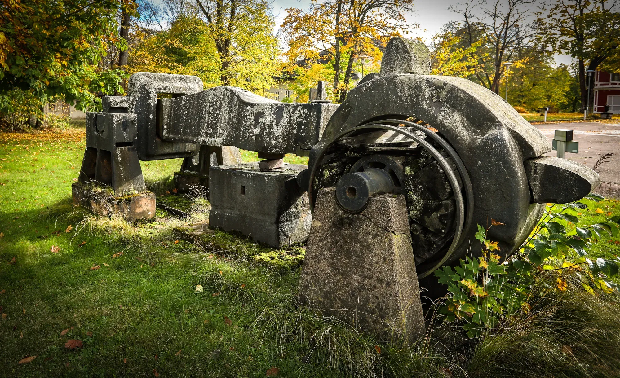 Gamla kvarnstenar och bruksmaskiner i gräset.
